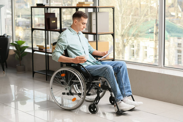 Junger Mann mit körperlicher Behinderung arbeitet im Büro - Foto, Bild