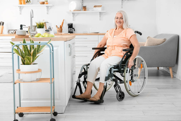 Dojrzała kobieta z niepełnosprawnością fizyczną w kuchni - Zdjęcie, obraz