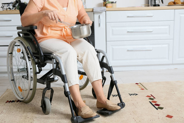 Зріла жінка з фізичною інвалідністю готує на кухні
 - Фото, зображення