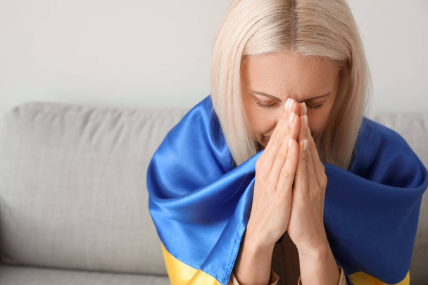 Starší žena s vlajkou Ukrajiny modlí doma, detailní záběr - Fotografie, Obrázek