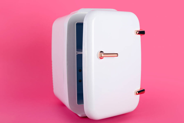 Pequeño refrigerador cosmético sobre fondo rosa - Foto, imagen
