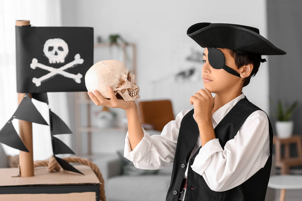 Продуманий маленький хлопчик, одягнений як пірат з людським черепом вдома
 - Фото, зображення