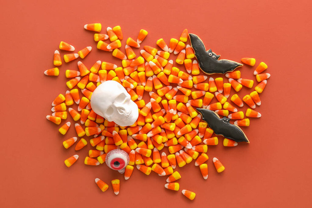 Halloween candy corns with cookies and skull on red background - Fotó, kép