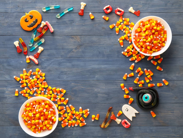 Frame made of bowls with Halloween jellies and cookies on dark wooden background - Photo, Image