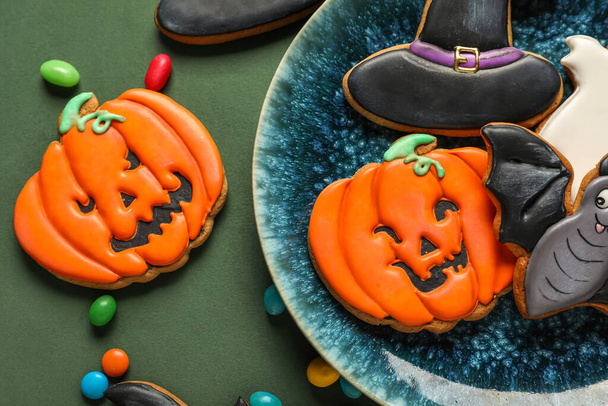 Bowl with Halloween cookies and candies on green background, closeup - Photo, Image
