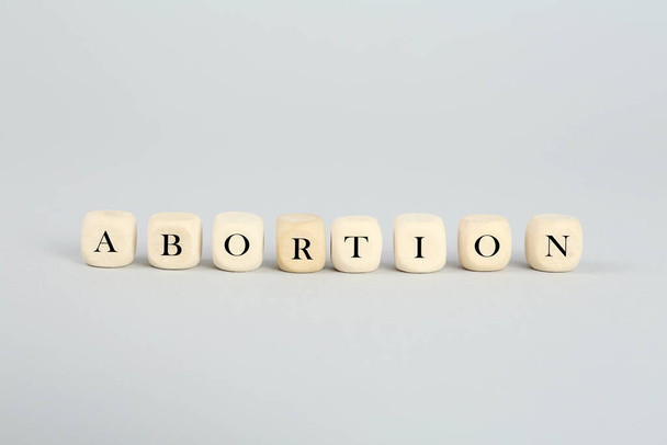 Word Abortion made of wooden cubes on light grey background - Φωτογραφία, εικόνα