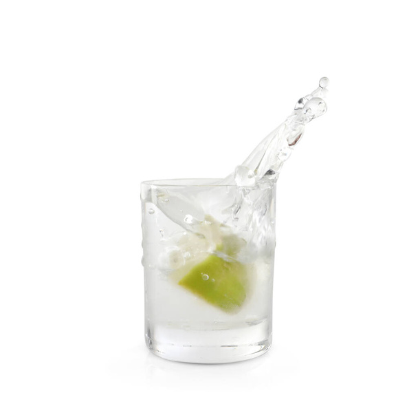Shot of vodka with lime slice and splash isolated on white - Фото, изображение