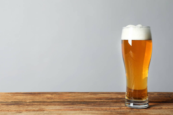 Un vaso de cerveza sabrosa sobre una mesa de madera. Espacio para texto - Foto, imagen