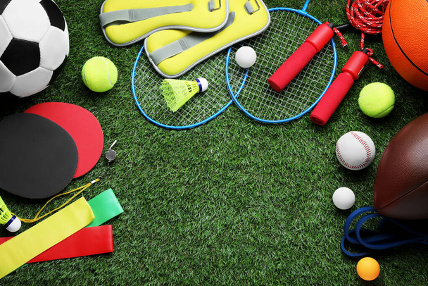 Set of different colorful sports equipment on green grass, flat lay. Space for text - Zdjęcie, obraz