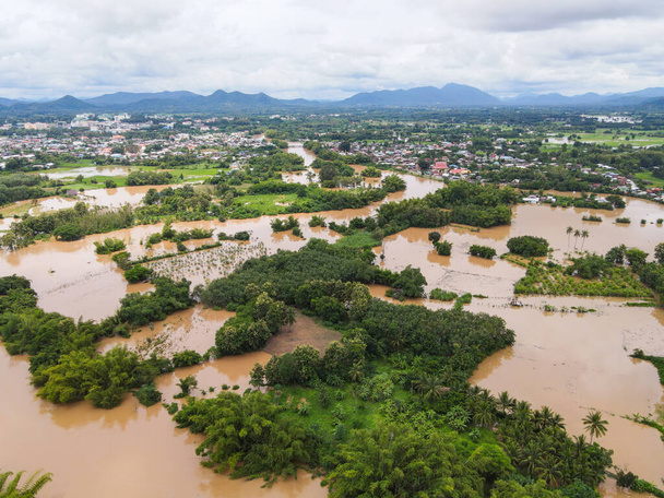 Luftaufnahme Fluss überschwemmt Dorflandschaft Asien und Waldbaum, Draufsicht Fluss mit Wasserflut von oben, Wildwasser fließt nach dem Regen den Dschungel hinunter - Foto, Bild