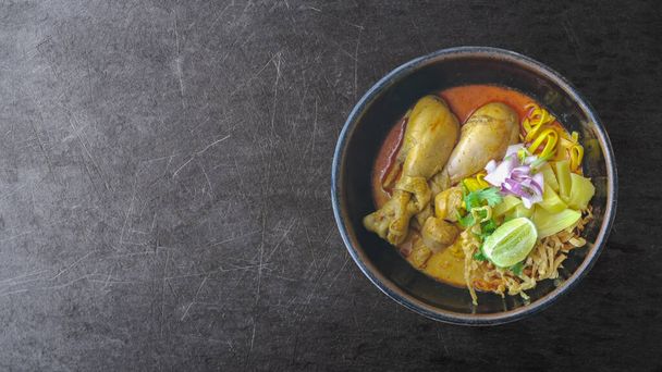 Fideos Khao soi o curry aislados sobre fondo de pizarra con camino de recorte, vista superior plana Sopa de fideos al curry de pollo, la soja Khao es una deliciosa sopa de coco y pasta de curry rojo - Foto, Imagen