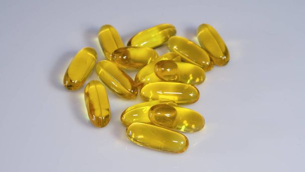 Cápsulas de vitamina E sobre fundo branco
 - Foto, Imagem