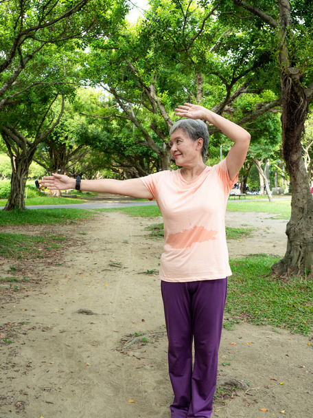 Portret szczęśliwej seniorki w podeszłym wieku Asia 60-latka wskazująca miejsce w parku. - Zdjęcie, obraz