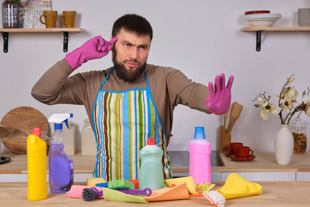 Bild eines jungen kaukasischen bärtigen Mannes in der Küche, macht er wenig Präsentation all seiner Reinigungsmittel und bereitet sich auf die große Reinigung vor - Foto, Bild