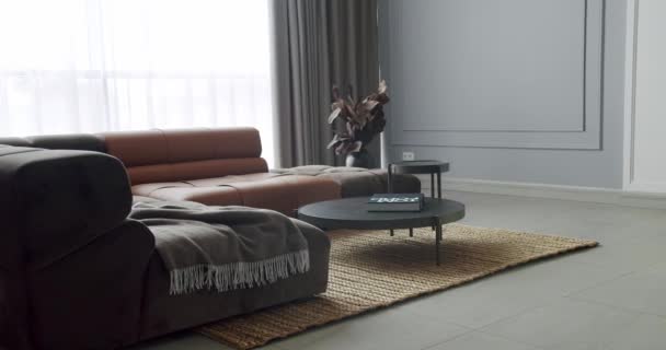 Современная гостиная в стиле минимализма с серой и коричневой мебелью. Роскошный современный дом с угловым диваном и круглым столом. Уютный современный дизайн мебели. Элегантный номер класса люкс - Кадры, видео