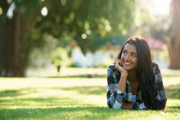 Entspannen im Park. Eine schöne junge Frau liegt im Gras in einem Park - Foto, Bild