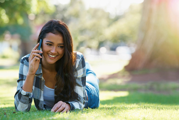 Im waiting in the park. an attractive young woman talking on the phone in a park - Foto, Bild