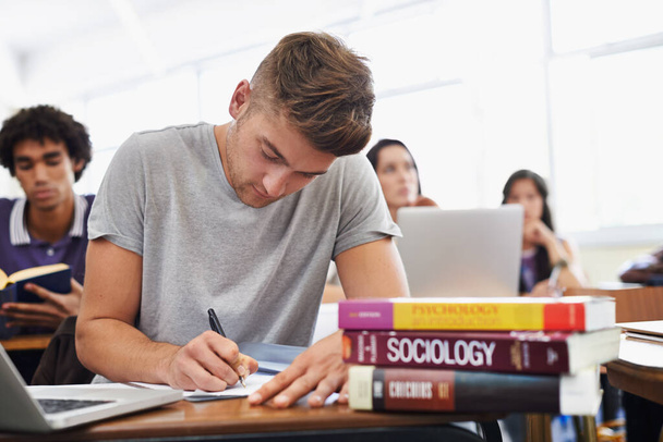 Seguro de éxito de estudio. Una joven estudiante guapa sentada en un escritorio con sus libros de texto - Foto, imagen