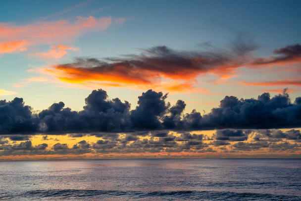 Hämmästyttävä auringonlaskun värit keltaisesta punaiseen ja sininen pilvien yli mereen. - Valokuva, kuva