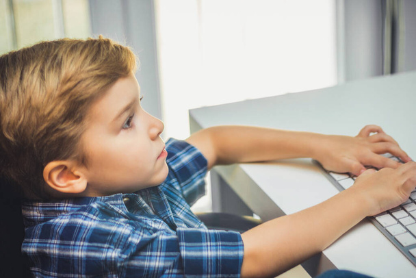 Egy kisgyerek számítógéppel és billentyűzeten gépel..  - Fotó, kép