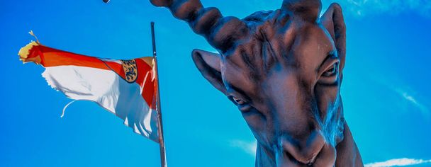 Rohatý zvířecí tvar s rakouskou vlajkou a modrou oblohou v pozadí - Fotografie, Obrázek
