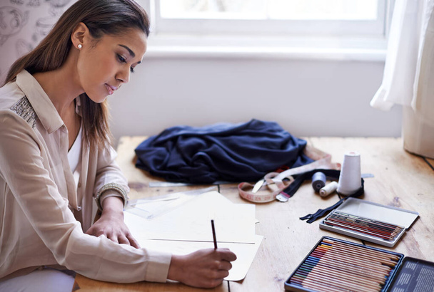 Δημιουργώντας αυτή την εποχή τάσεις. Μια νεαρή σχεδιάστρια μόδας κάνει σκίτσα στο γραφείο της. - Φωτογραφία, εικόνα