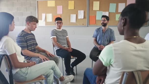 Studenti delle scuole superiori adolescenti che parlano e ascoltano giovani insegnanti maschi - Conversazione di supporto di gruppo nell'istruzione superiore - Filmati, video