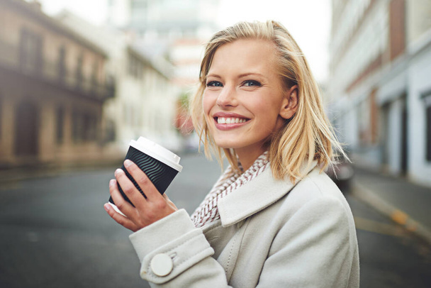 A városi élet az életem. Vágott portré egy vonzó fiatal nőről, aki kávét iszik, miközben a város utcáin sétál. - Fotó, kép