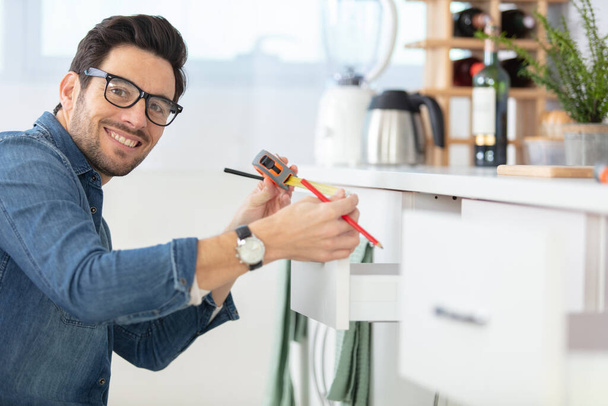 man measuring drawer size in kitchen - Photo, Image