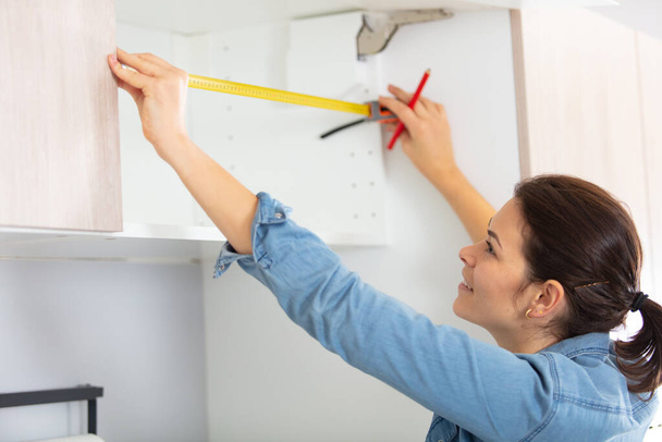 woman measure kitchen shelf at home - Foto, imagen