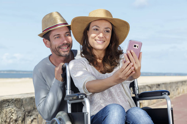 husband and woman in wheelchair doing a selfie - Foto, Imagen