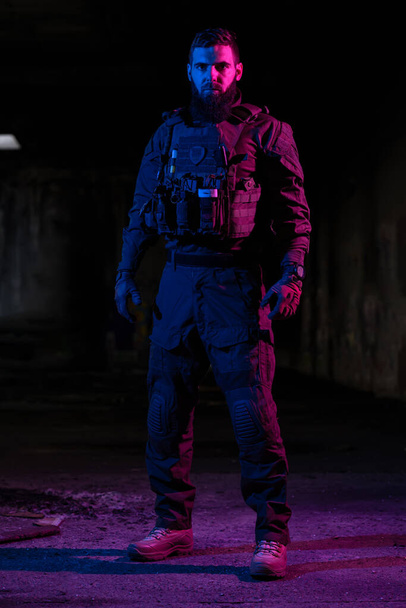 Army soldier in Combat Uniforms with an assault rifle and combat helmet night mission dark background. Blue and purple gel light effect. High quality photo - Zdjęcie, obraz