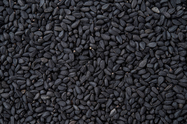 Black cumin macro texture. Whole nigella seeds closeup background. Dry kalonji fruits for food design and cooking. Concept of organic spice and seasoning. Medicinal herb nigella sativa. Top view. - Photo, Image