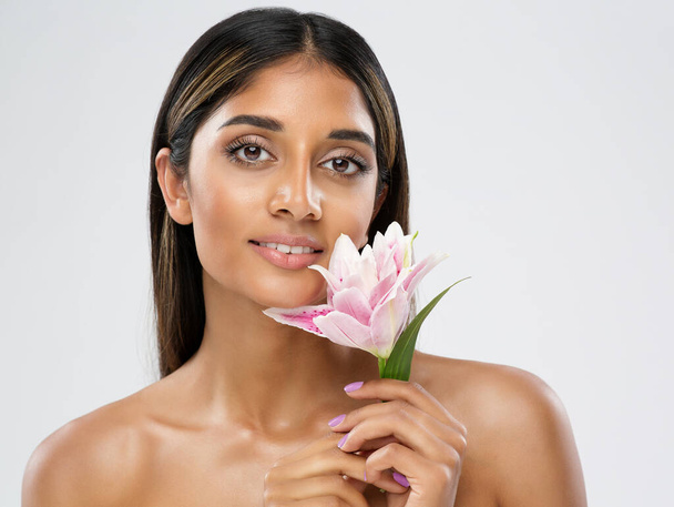 Face Skin Care. Beauty Indian Model smelling Lotus Flower. Beautiful Woman Portrait with Natural Make up and smooth Skin. Women Facial Spa Massage Cosmetology over White - Valokuva, kuva