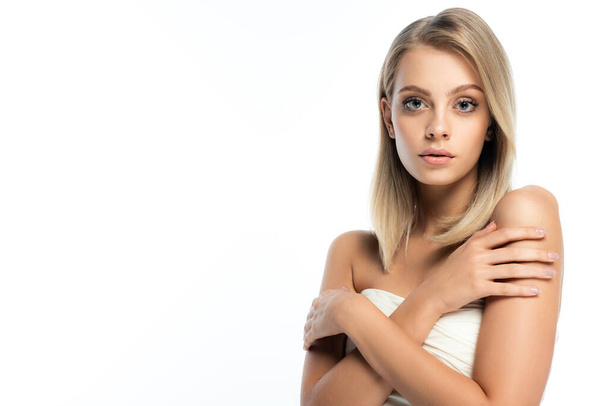 portrait of blonde woman with natural makeup and bare shoulders posing with crossed arms isolated on white - Fotó, kép