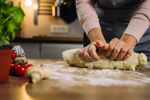 close up of woman prepares dough in her kitchen - Foto, afbeelding