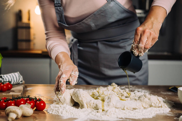 close up of woman prepares dough in her kitchen, adding oil - Zdjęcie, obraz