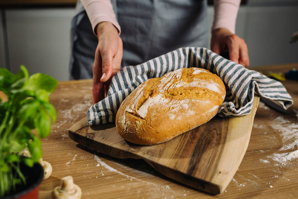 mujer sosteniendo recién hecho en casa pan horneado en su cocina - Foto, Imagen