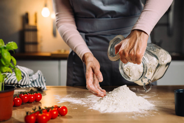 close up of woman prepares dough in her kitchen - Foto, afbeelding