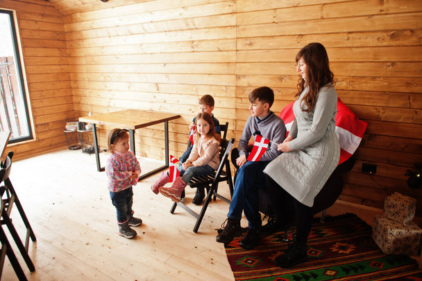 Family with Denmark flags inside wooden house. Travel to Scandinavian countries. Happiest danish people's . - 写真・画像