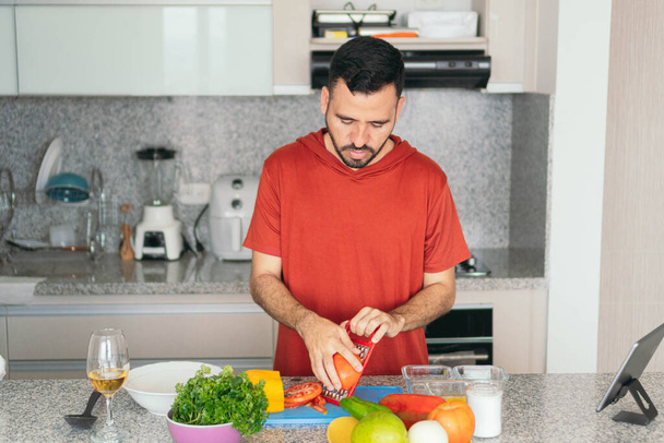 Νεαρός μαγειρεύει μια υγιεινή σαλάτα με φρούτα και λαχανικά. - Φωτογραφία, εικόνα