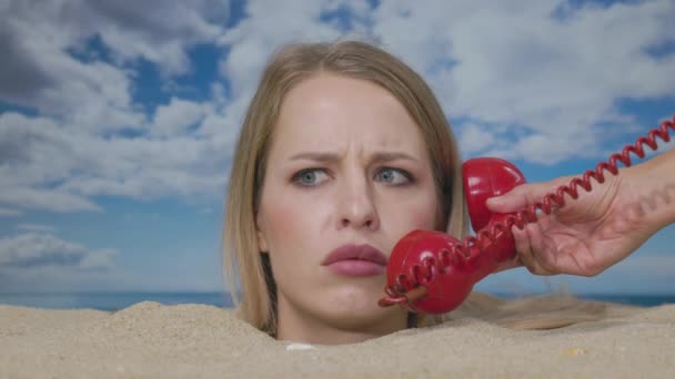 Kumsalda boğazına kadar gömülmüş güzel bir kadın kırmızı bir telefondan rahatsız edici haberler alıyor. - Video, Çekim