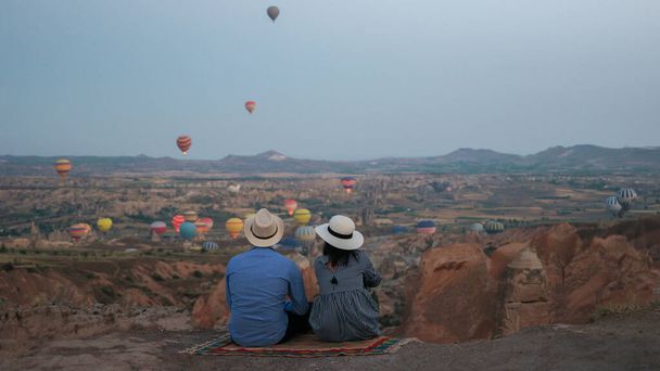 Asian women and caucasian men mid age on a trip to Kapadokya Cappadocia Turkey, a happy young couple during sunrise watching the hot air balloons of Kapadokya Cappadocia Turkey during vacation - Photo, Image