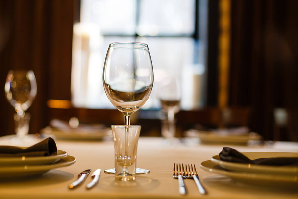 Restaurant of cafe tafel set voor feest, banket, feest, receptie. Wijnglas en borrelglas, bestek, witte borden. Tafelopstelling - Foto, afbeelding