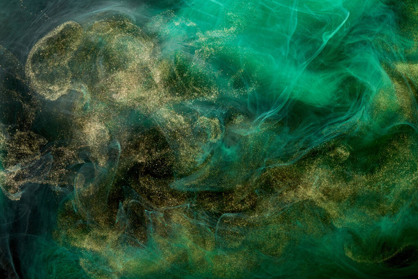 Golden sparkling abstract background, luxury green smoke, acrylic paint underwater explosion, cosmic swirling ink - Foto, immagini