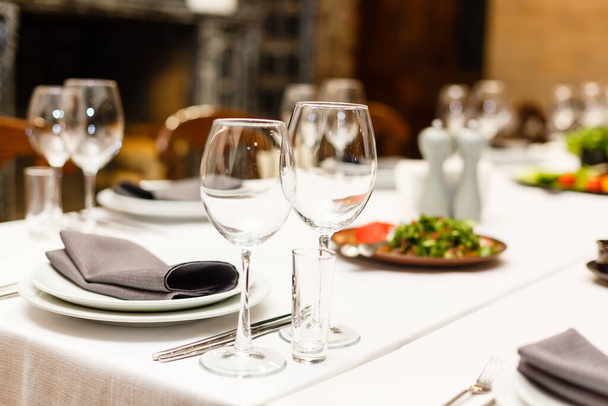 Table de restaurant pour fête, banquet, fête, réception. Verres à vin, verres à verre, couverts, assiettes blanches. Soirée romantique extérieure - Photo, image