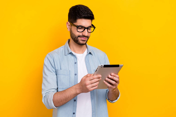 Portrait of young guy wear denim shirt holding tablet online education student isolated on bright yellow color background. - Fotografie, Obrázek