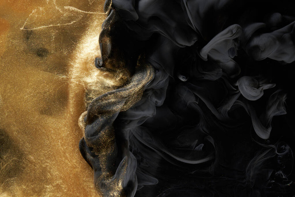 Golden sparkling abstract background, luxury black smoke, acrylic paint underwater explosion, cosmic swirling ink - Foto, Bild