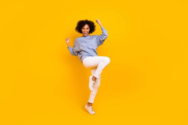 Full body portrait of overjoyed delighted girl raise fists celebrate luck triumph isolated on yellow color background. - Foto, imagen