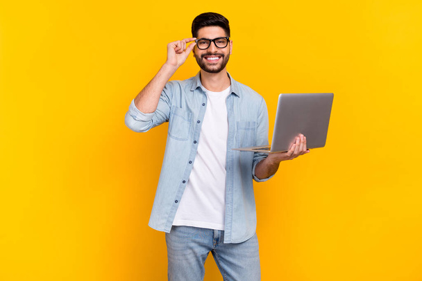 Photo of cheerful latin young guy touch eyewear visit remote work conference wear stylish denim look isolated on yellow color background. - Фото, зображення